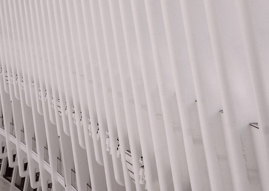 Weißer symmetrischer Architekturkorridor als Sinnbild für die Spaltung von Versicherungsunternehmen